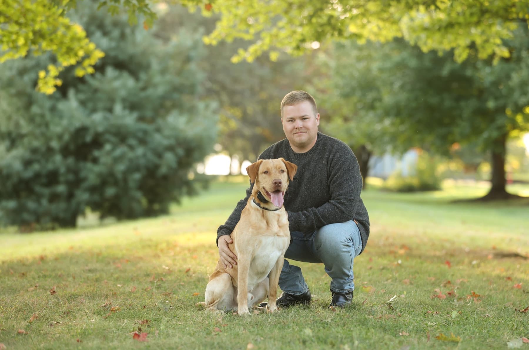Ryan Gouger kneeling with Kash, the Gouger's Tree Care shop dog